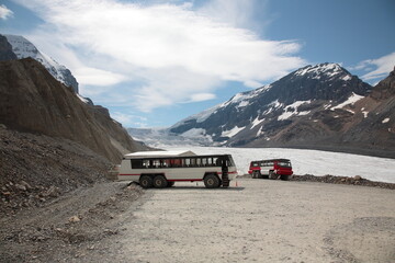 View of Athabasca Glacier with snow mountain peaks and Ice Explorer massive vehicle snow coach bus...