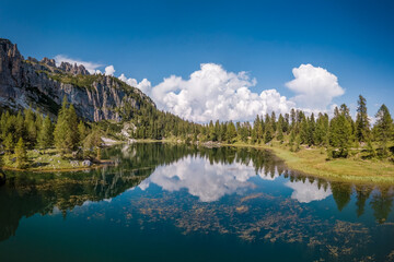 Blue sky and white clouds reflections in lake Croda da Lago, in Cortina d'Ampezzo in the Dolomites, Italy