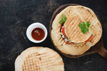 Top view of doner kebab pitas on a dark brown stone background, horizontal shot with space