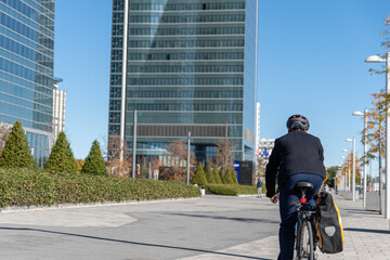 A shot of the back of a businessman going to work at the offices by bicycle. Concept on the environment and more sustainable cities