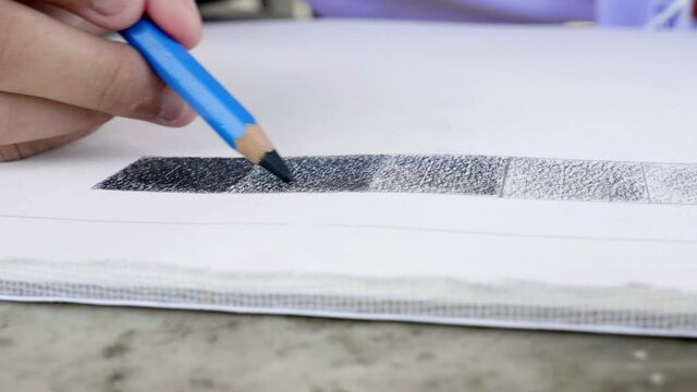 Student is doing drawing practice to practice the basics of light and shadow, using black pencil shading.