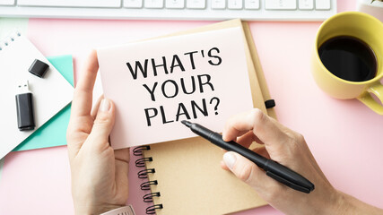 What's Your Plan question written on notebook paper and office supplies on black background. Business concept.