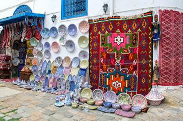 Typical Tunisian souvenir shop with ceramics and carpets on the wall