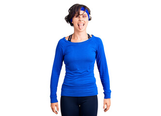 Beautiful young woman with short hair wearing training workout clothes sticking tongue out happy with funny expression. emotion concept.