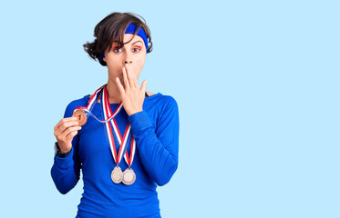 Beautiful young woman with short hair wearing winner medals covering mouth with hand, shocked and afraid for mistake. surprised expression