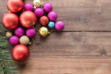 Happy New Year and Christmas Concept. Flat lay view of colorful red, pink, blue, yellow ornament ball and mockup xmas tree on wooden plank with copy space for text.