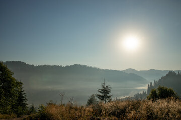 Fototapeta premium Beautiful sunrise in mountains with white fog below panorama