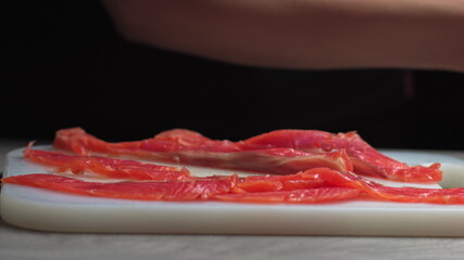 male chef cuts fillet of fresh salmon into large chunks. Cooking fish in kitchen. Preparation of ingredients by chef to prepare dish. Cooking in the restaurant kitchen. Food ingredients for gourmets