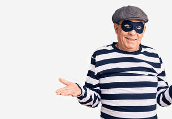 Senior handsome man wearing burglar mask and t-shirt smiling showing both hands open palms, presenting and advertising comparison and balance