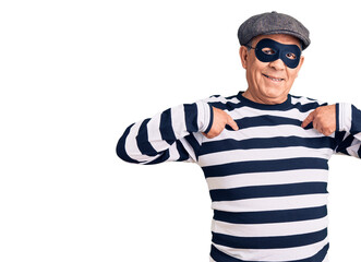 Senior handsome man wearing burglar mask and t-shirt looking confident with smile on face, pointing oneself with fingers proud and happy.