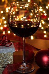 Glass of red wine with Christmas lights reflecting in background