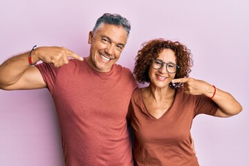 Beautiful middle age couple together wearing casual clothes smiling cheerful showing and pointing with fingers teeth and mouth. dental health concept.