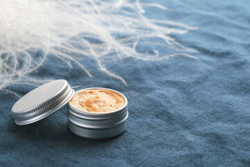 Jar of natural cosmetic product on blue linen fabric