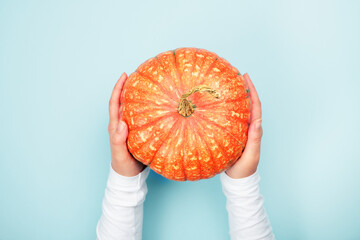 Female hands holding ripe orange pumpkin