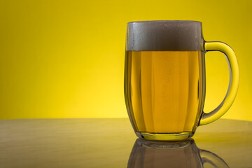 A glass of light beer on a yellow background.