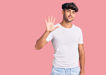 Young hispanic man wearing casual clothes showing and pointing up with fingers number five while smiling confident and happy.