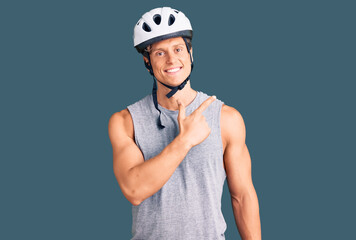 Young handsome man wearing bike helmet cheerful with a smile of face pointing with hand and finger up to the side with happy and natural expression on face