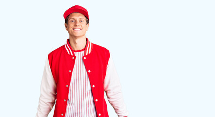 Young handsome man wearing baseball uniform looking positive and happy standing and smiling with a confident smile showing teeth