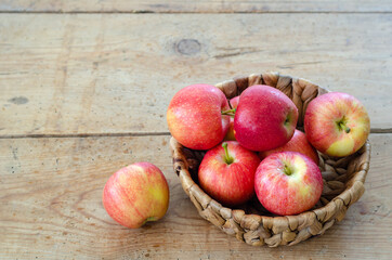 Red apples are in the basket on wooden table