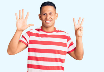 Young handsome latin man wearing casual clothes showing and pointing up with fingers number eight while smiling confident and happy.