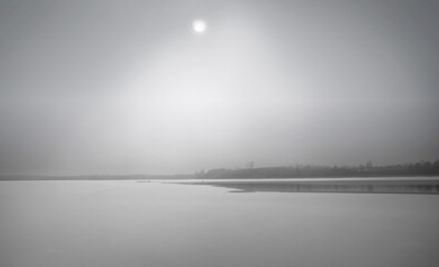 Ethereal winter scene of weak sun burning through  fog and haze over frozen Rideau River nobody