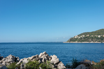View on the coast of mediterranean sea under blue sky. Rocks in the foreground....
