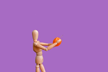 A wooden mannequin holds a physalis flower in his hands.