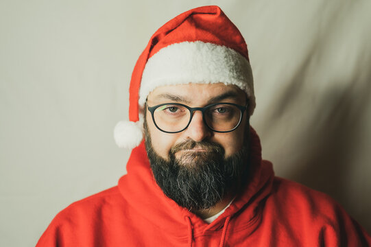 Man with Christmas hat looks annoyed at the camera