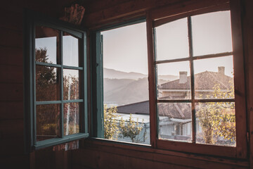Open window with dirty glass in rural house. View from window to mountains. Interior of countryside building. Village architecture. Autumn in mountain village. Sunlight in open window. 