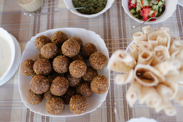 A table spread of middle-eastern dishes like hummus and falafel and salad