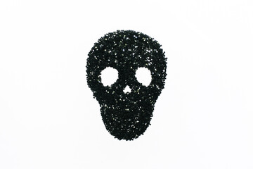 Skull consisting of black confetti in the shape of stars on a white background. Halloween concept. Flat lay, top view.