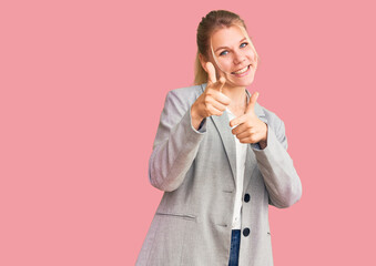 Young beautiful blonde woman wearing elegant jacket pointing fingers to camera with happy and funny face. good energy and vibes.