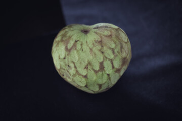 Obraz premium Cherimoya on black background. Annona cherimola. Seasonal fruit. Heart shape fruit.
