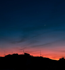 Obraz premium Beautiful blue and orange sunset with moon. Black cityscape.
