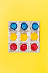 Composition with colorful condoms on yellow background. Safe sex and contraceptive concept. Flat...