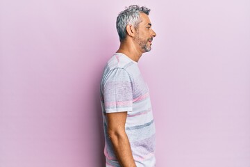 Middle age grey-haired man wearing casual clothes looking to side, relax profile pose with natural face with confident smile.