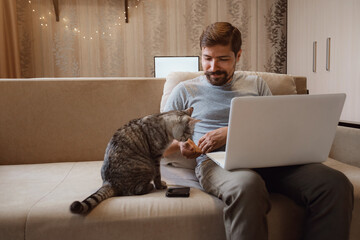 Young attractive smiling guy is browsing at his laptop