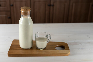Obraz na płótnie Canvas milk bottle and a glass on the kitchen table. Milk on a wooden board indoors.Organic farmer's Breakfast