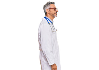 Middle age grey-haired man wearing doctor uniform and stethoscope looking to side, relax profile...