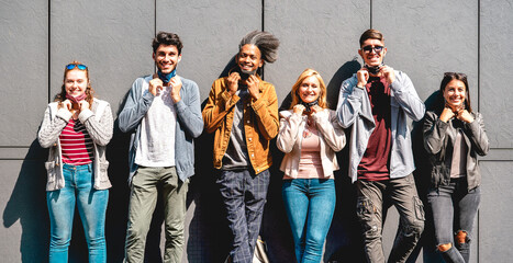 Fototapeta premium Multiracial friends smiling with face mask after lockdown reopening - Happy guys and girls having fun around city streets - University students on sunny day at urban wall - Warm bright filter