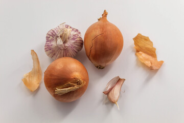 Two whole bulbs with husks and one small garlic on a white background