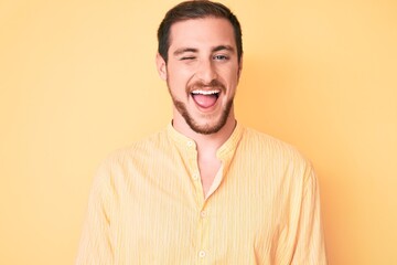 Young handsome man wearing casual clothes winking looking at the camera with sexy expression,...