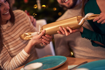 Group of friends celebrating Christmas by pulling crackers