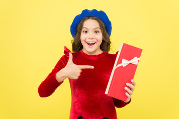 look at that. successful shopping time. happy childhood. smiling french teen girl in beret pointing finger on present box. parisian kid with gift. elegant child having birthday. fashion and beauty