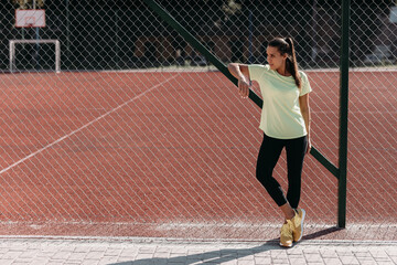 Charming woman in sport outfit standing at stadium