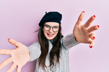 Young beautiful caucasian girl wearing french look with beret looking at the camera smiling with open arms for hug. cheerful expression embracing happiness.