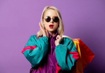 Style woman in 80s windbreaker and roud sunglasses hold shopping bags