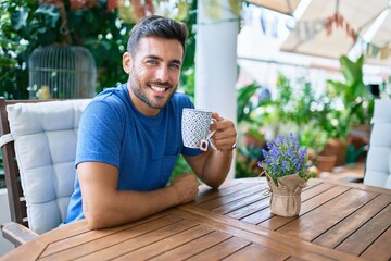 Young hispanic man drinking cup of tea sitting on the table at the terrace.