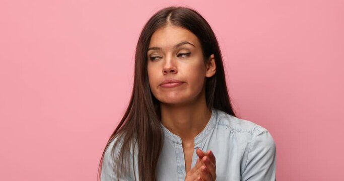 arrogant casual woman wearing blue denim shirt clapping and congratulating in a superior manner on pink background