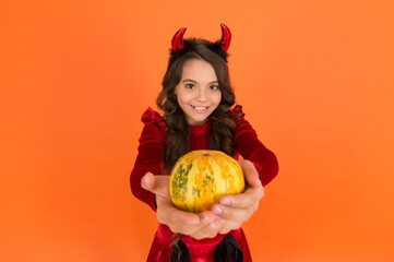 happy halloween devil girl. teenage child in imp horns. cheerful kid carry pumpkin. making jack o lantern. carnival costume party. trick or treat. celebrate the holidays. childhood